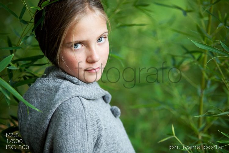 IF.EU – BLOG – Articolo 02 – 03 Ho scattato quest’immagine per il prestigioso marchio di abbigliamento per bambini “Kid’s Company” ed è stata pubblicata su Vogue Bambini.
Ero diventata fotografa professionista da poco e, capirete, fotografare per un marchio importante può creare in un fotografo “giovane” un certo imbarazzo, soprattutto sulla scelta del set e dello schema di luci.
Siamo abituati a pensare che la fotografia di moda debba essere realizzata con complessi set, studio e team a disposizione.
Molto di questo scatto si deve a Francesca, la mia giovane modella, paziente e brava. Moltissimo, invece, all’accuratissima scelta della luce e dello sfondo. Questa morbida e magica luce che illumina il suo viso e da un senso di meraviglia all’immagine. Sembra come se fosse circondata dai giganti diffusori, panelli e altro, ma non c’è null’altro che un’ombra morbida all’interno di questa grande siepe di bambù!